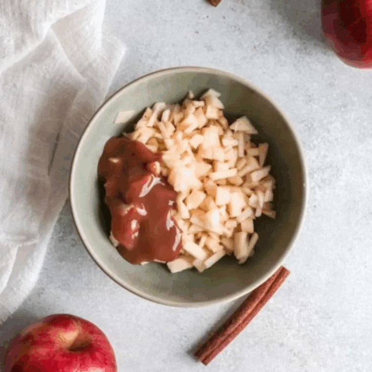 Apples coated in caramel sauce beside rolled dough rectangle ready for filling