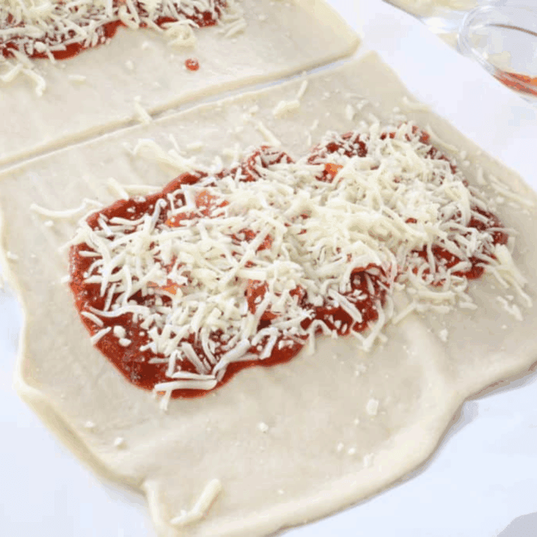 Even layer of pizza sauce on dough topped with shredded mozzarella cheese.