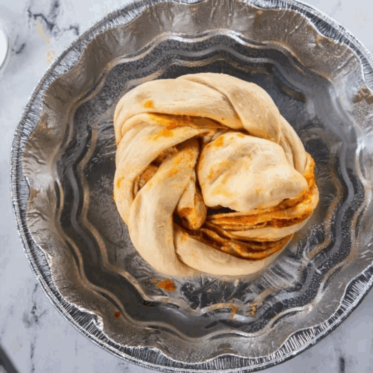 pumpkin spice bread twist baking in air fryer at 320 degrees in parchment-lined pan