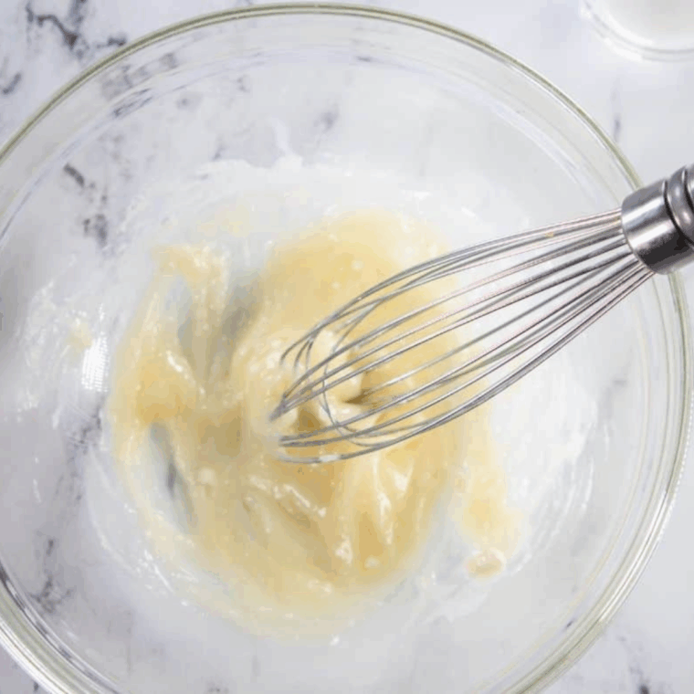 cream cheese icing being mixed and drizzled over warm pumpkin spice bread twist