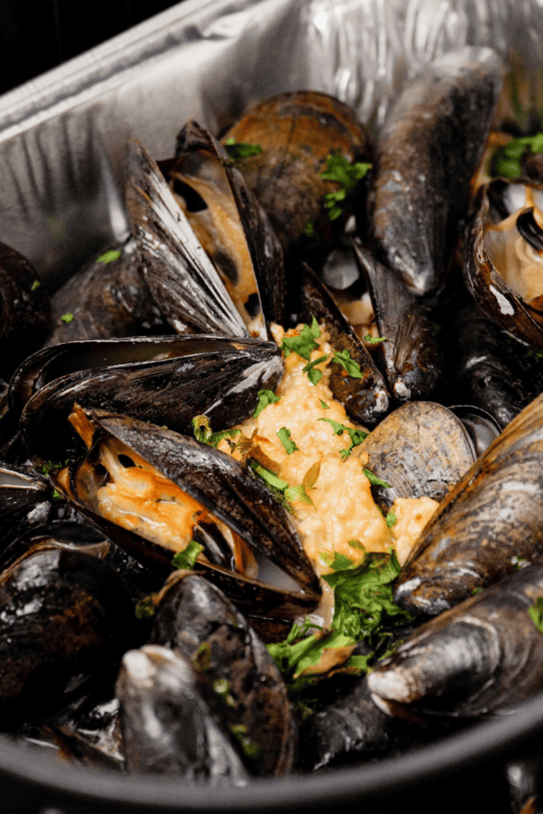 Easy Bonefish Grill Mussels in garlic butter served in a white bowl with parsley garnish.