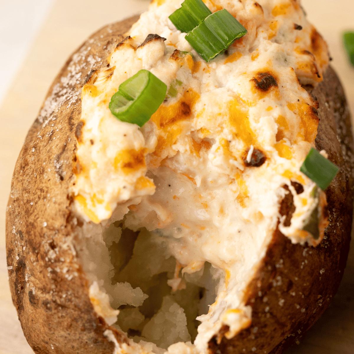 Golden baked potato with crispy skin, topped with butter and herbs