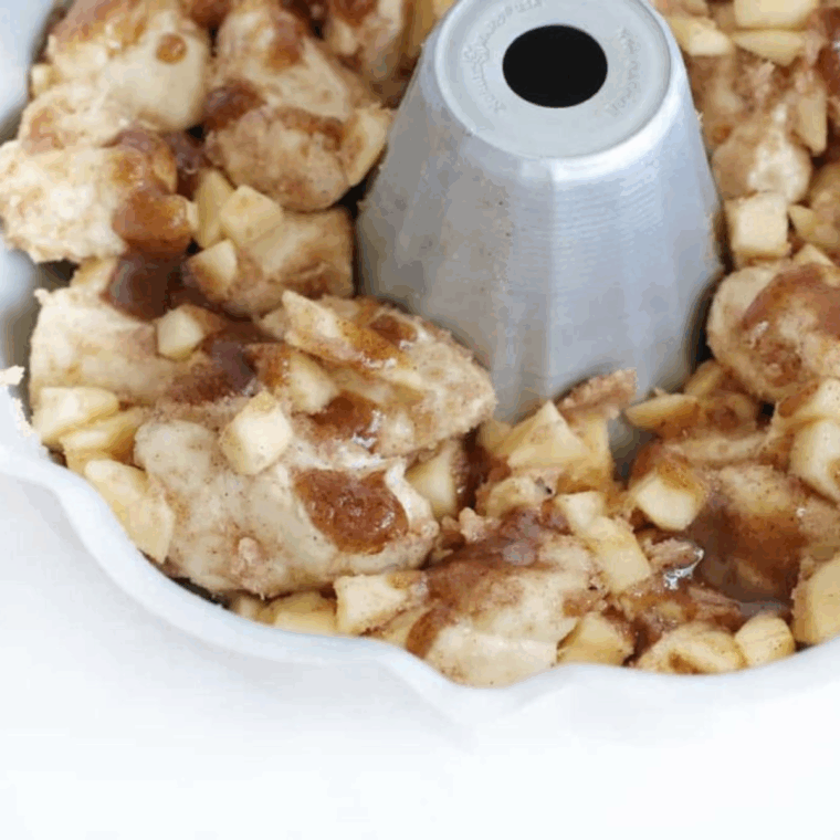 Apple-coated biscuit pieces transferred into a greased Bundt pan, ready to air fry until golden brown and fully cooked.