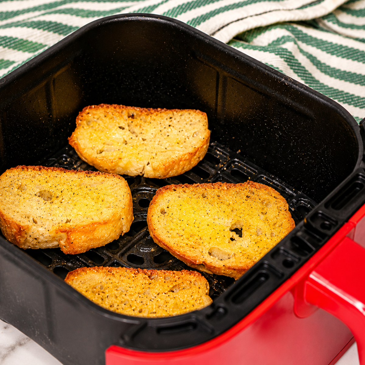 Golden crostini in the air fryer basket after four minutes at 400 degrees
