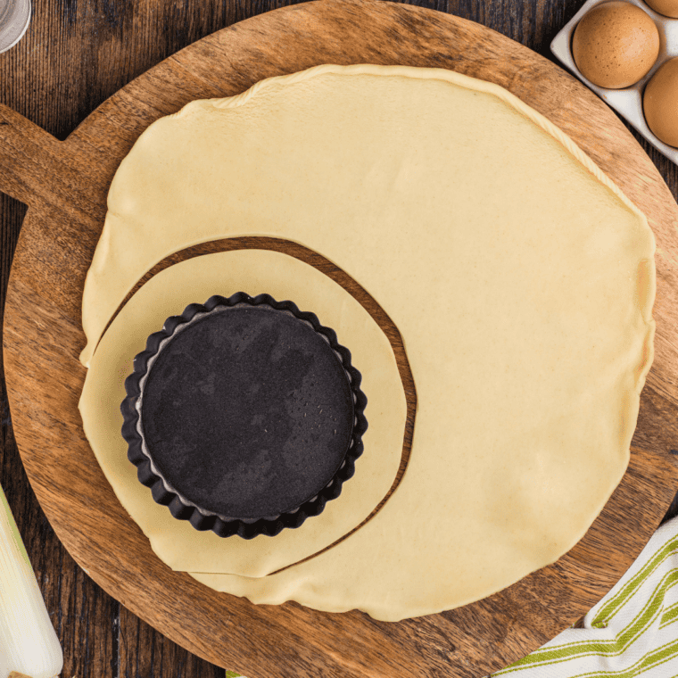 Pie crust dough cut into a circle around a small removable-bottom tart pan.