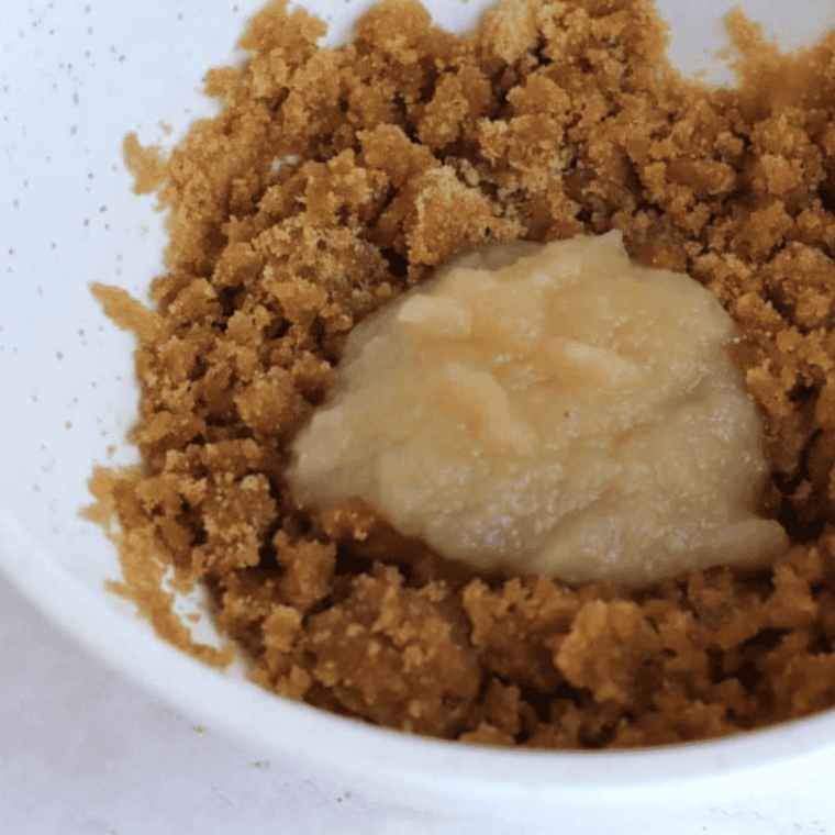 Mixing butter, apple pie spice, vanilla, brown sugar, applesauce, and egg in a bowl for oatmeal cookie dough.