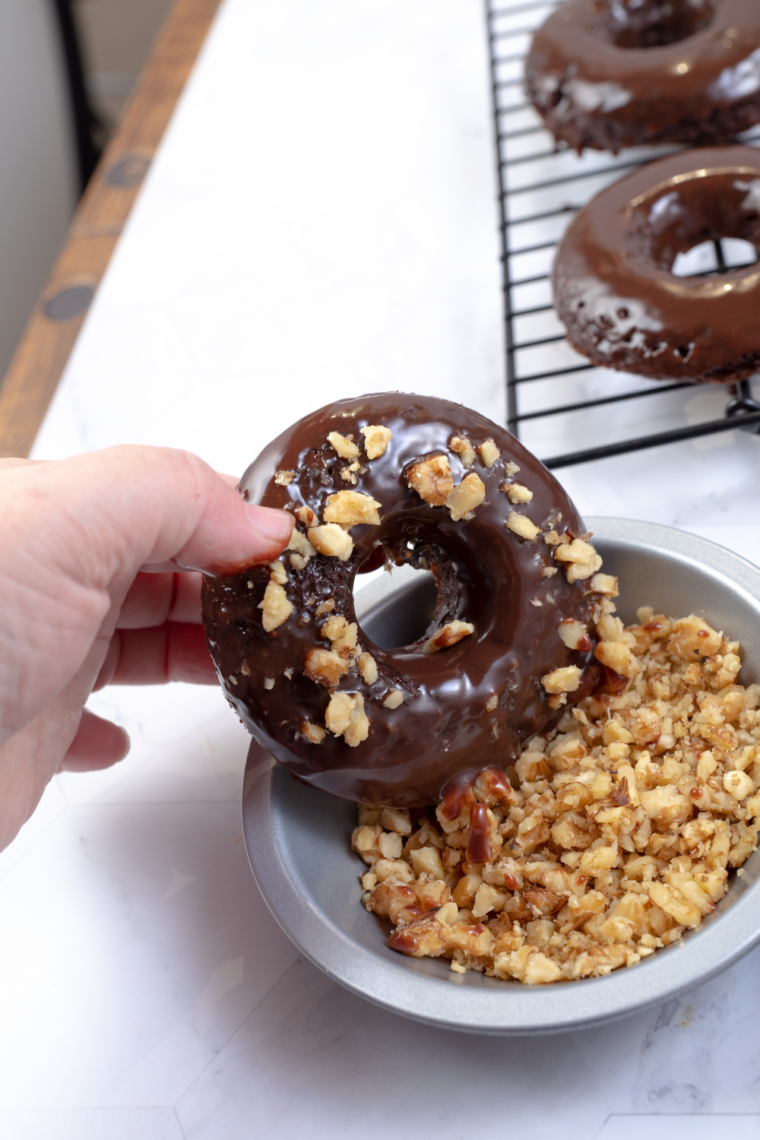 coating air fryer brownie donuts in chocolate and nuts before setting on wire rack