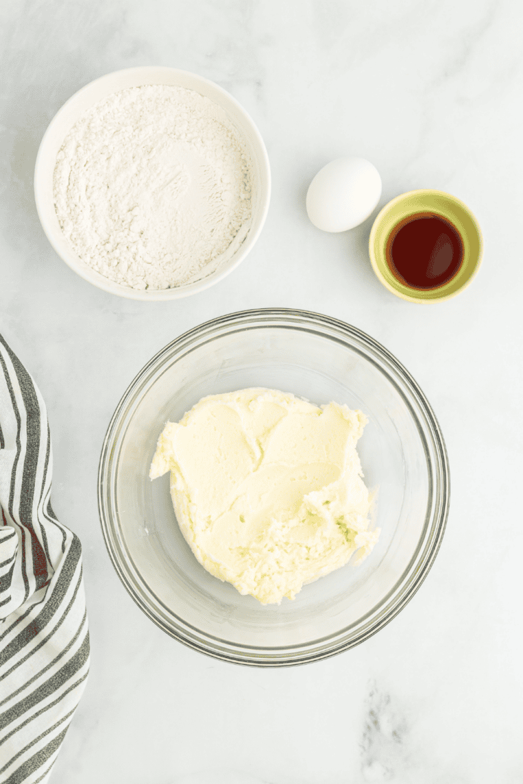 Preparing dough for snickerdoodle cookie fries, mixing dry ingredients in one bowl and creaming butter with sugar in another, with parchment-lined baking sheets ready.