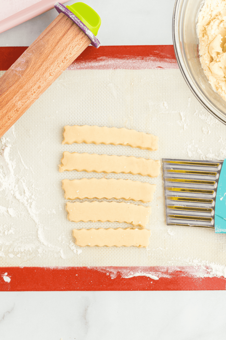Rolling out snickerdoodle cookie dough to 3/8&rdquo; thickness on lightly floured surface using a rolling pin for even, thick, chewy cookies.