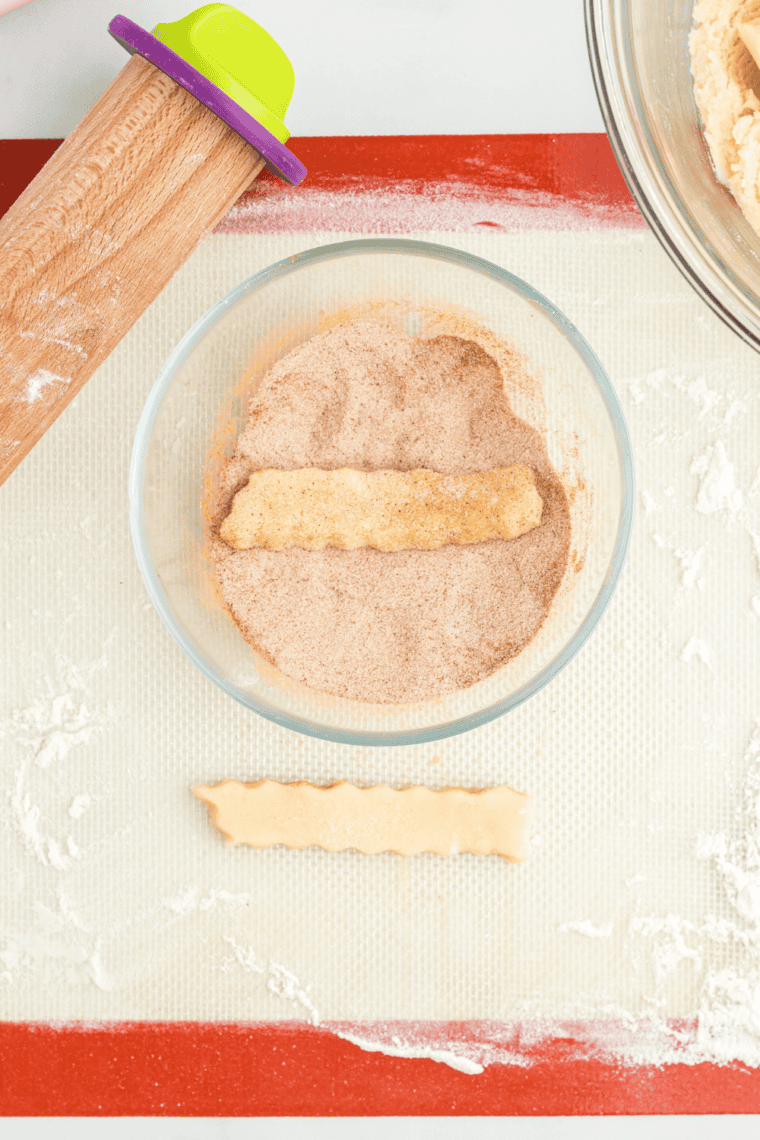 Rolling out a portion of snickerdoodle dough and cutting cookie fries &frac12;&rdquo;&ndash;&frac34;&rdquo; wide and 4&rdquo;&ndash;5&rdquo; long with a crinkle cutter.