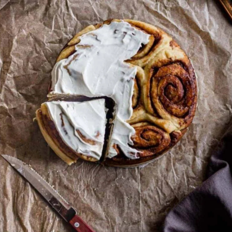 Maple coffee frosting being poured over warm Pioneer Woman cinnamon rolls