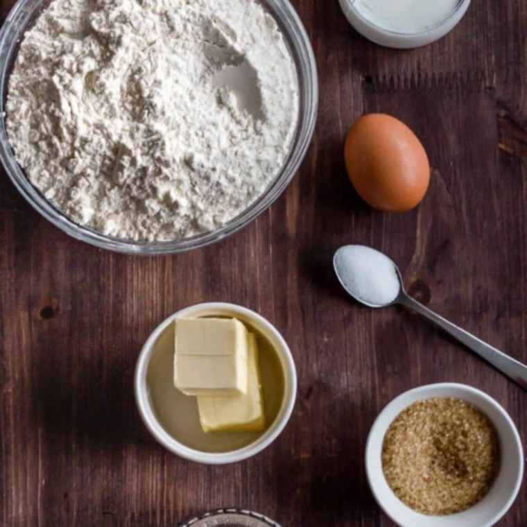 Ingredients for Pioneer Woman cinnamon rolls on a counter, including flour, milk, yeast, butter, sugar, cinnamon, and maple flavoring