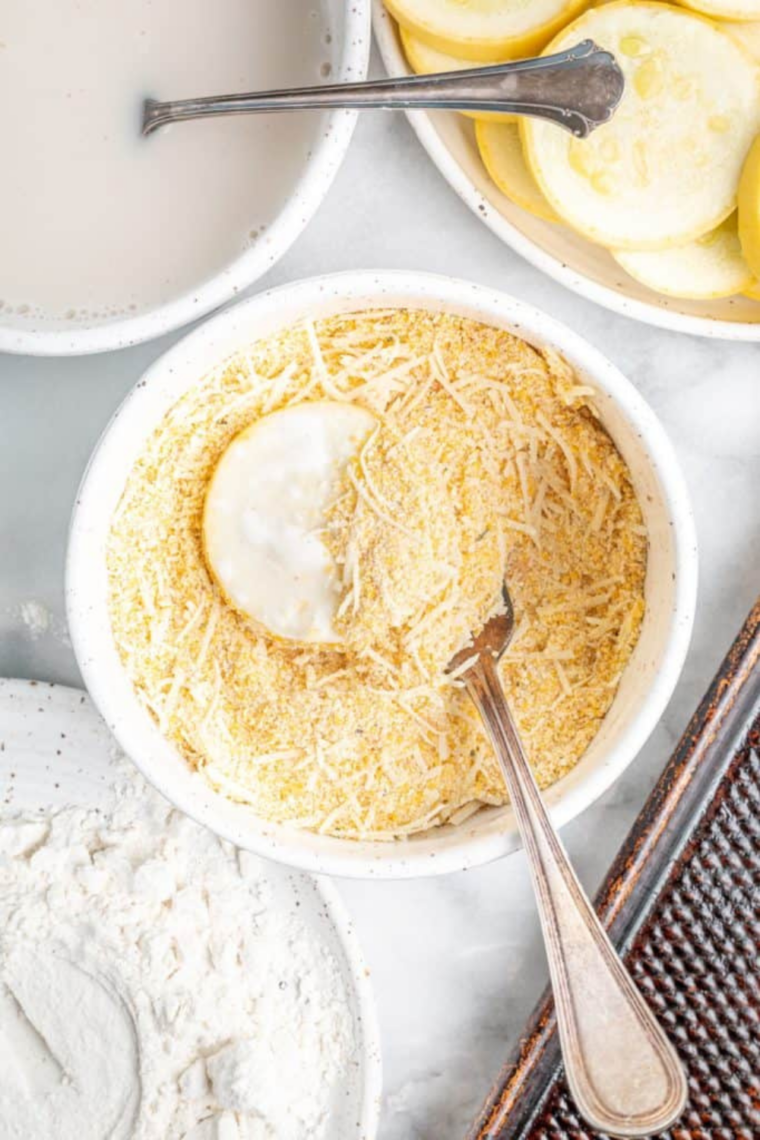 Squash pressed into cornmeal Parmesan seasoning mixture for crispy coating finish