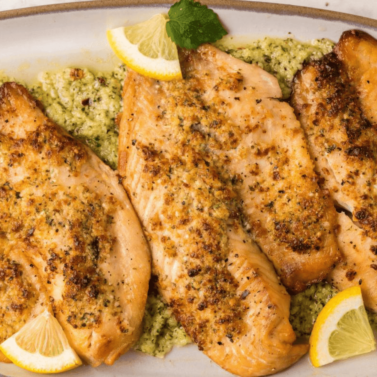 Golden, crispy air fryer frozen tilapia fillets served with lemon wedges and fresh herbs.