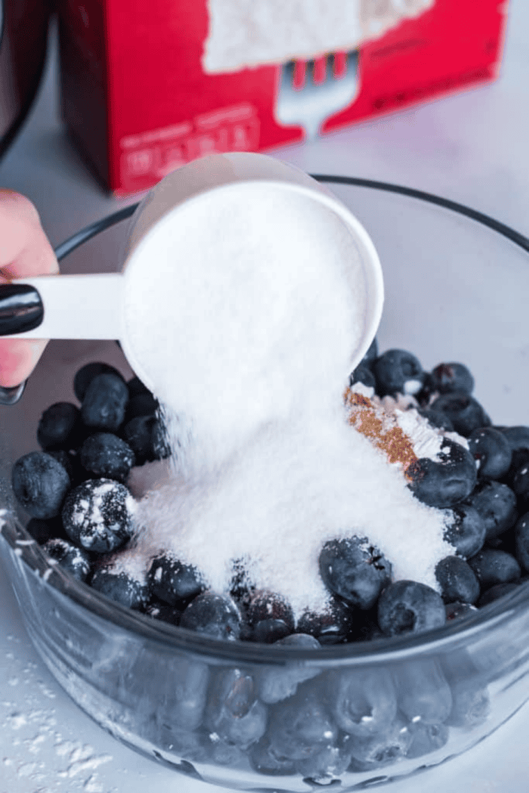 Butter cut into small pats placed evenly over dry cake mix in a pan, preparing Instant Pot blueberry cake for baking.