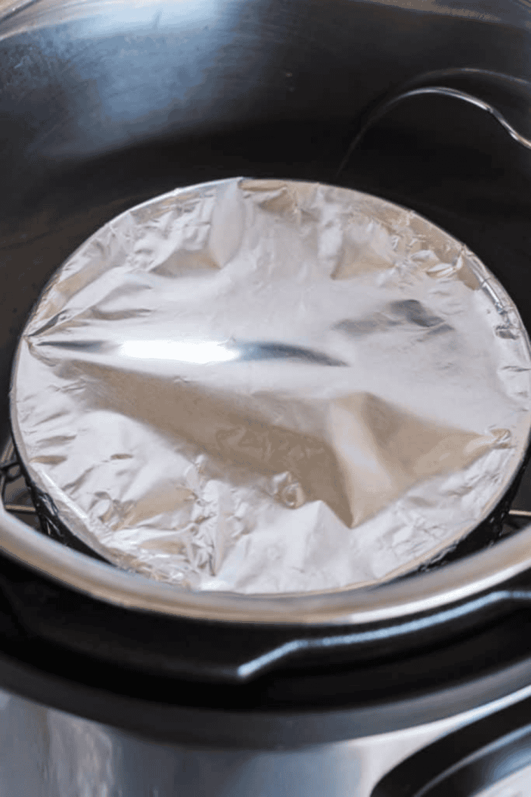 Instant Pot with water added to the bottom and trivet inserted, with cake pan placed on top ready for steaming blueberry cake.