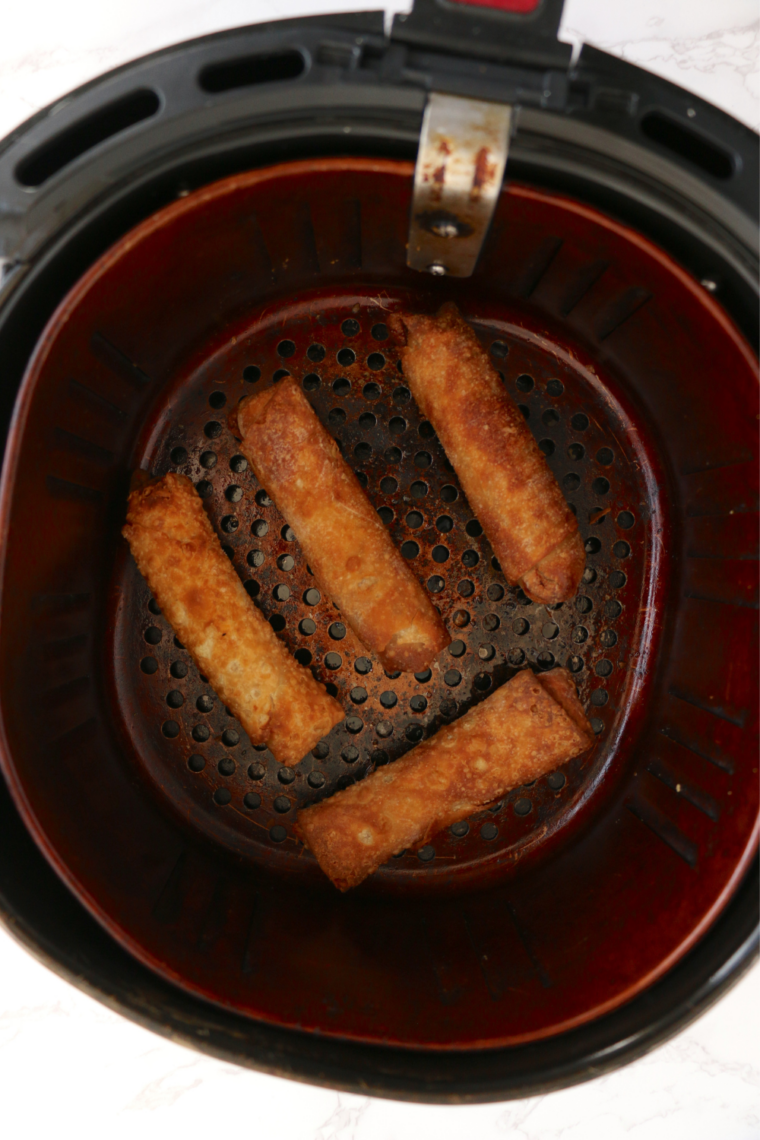 Crispy cooked egg rolls resting on a plate with dipping sauce