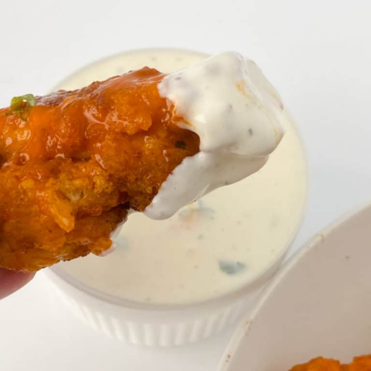 Chicken pieces arranged in an air fryer basket with space between them, ready to cook in batches for even crisping.
