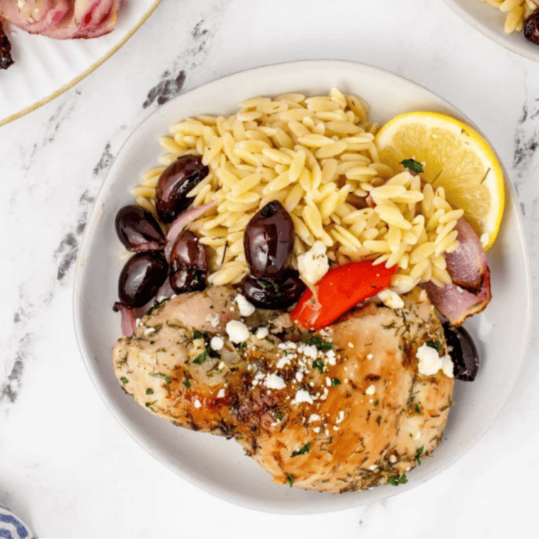 Overhead view of Air Fryer Greek Chicken with red bell pepper, red onion, kalamata olives, and feta on a serving plate