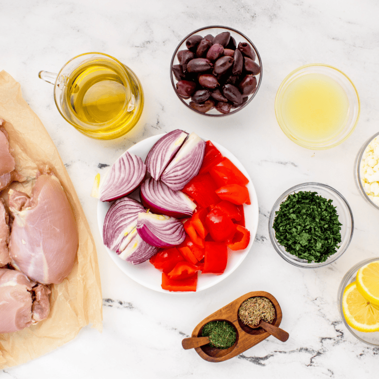 Ingredients for Air Fryer Greek Chicken with summer vegetables: chicken thighs, red bell pepper, red onion, kalamata olives, olive oil, lemon, thyme, dill, and feta