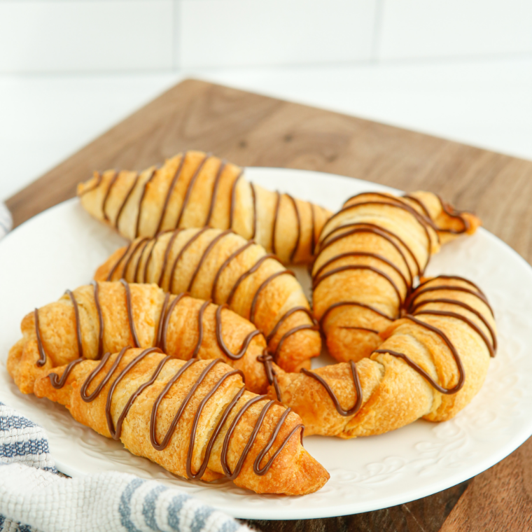 Plate of air fryer peanut butter chocolate crescent rolls drizzled with chocolate sauce