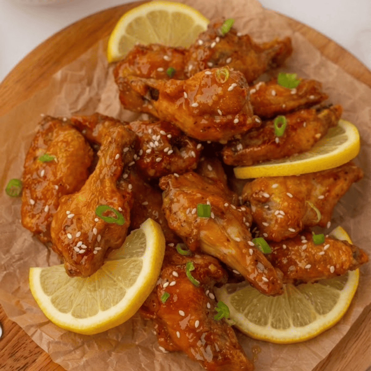 Crispy copycat Hooters lemon pepper wings piled on a plate with fresh lemon wedges