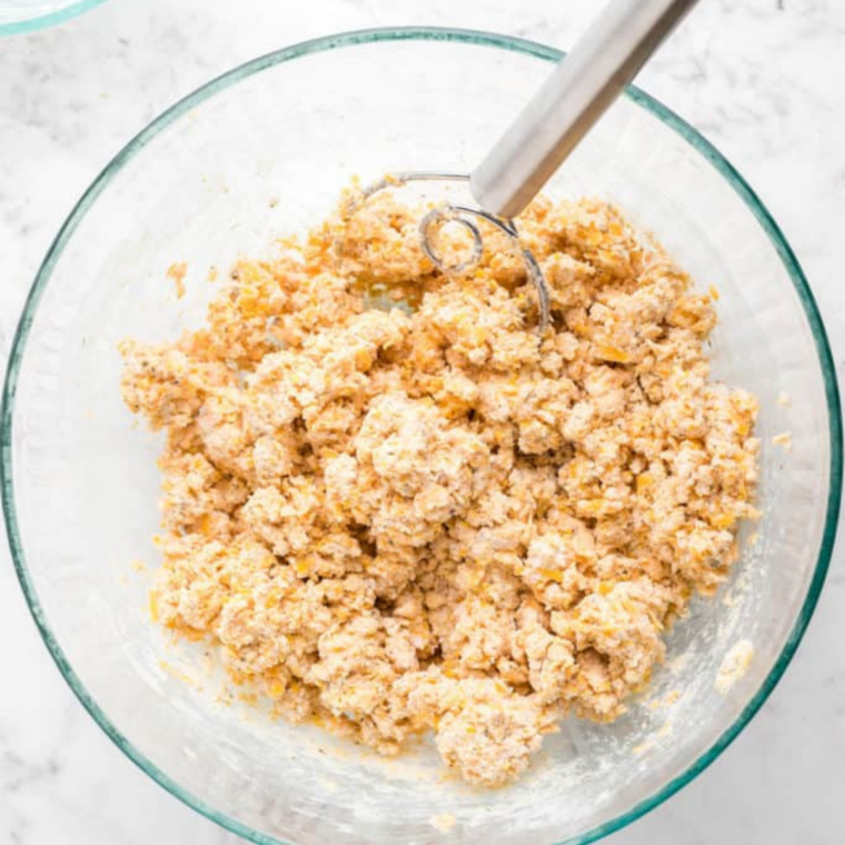 Whisking flour, baking powder, salt, garlic powder, and pepper in a mixing bowl