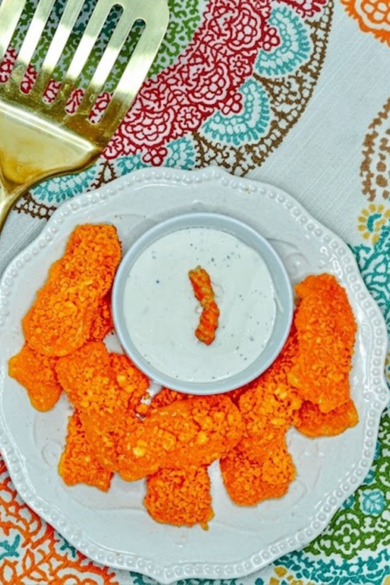 Air fryer mozzarella sticks coated in crushed Cheetos golden crispy spicy snack with melted cheese pull appetizer.