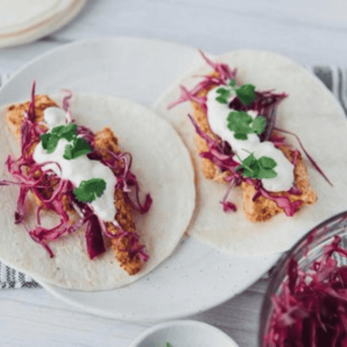 Close-up of homemade Blackened Baja Fish Tacos with crispy seasoned fish, fresh slaw, and zesty sauce on tortillas.