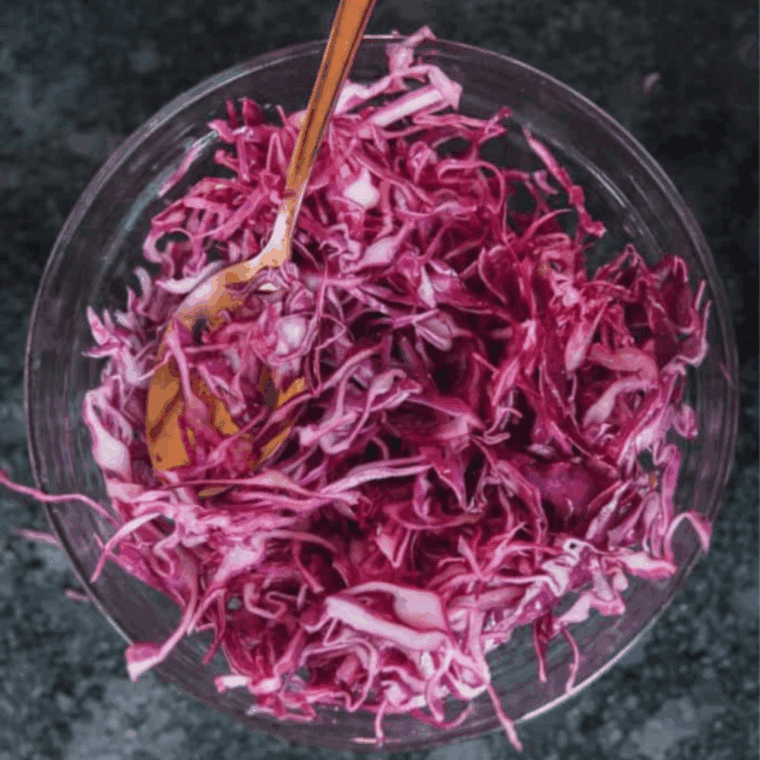Mixing shredded cabbage with lime juice, vinegar, honey, salt, and pepper to make refreshing slaw.