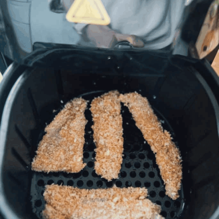 Placing seasoned fish strips in a single layer in the air fryer basket, cooking until golden and flaky.