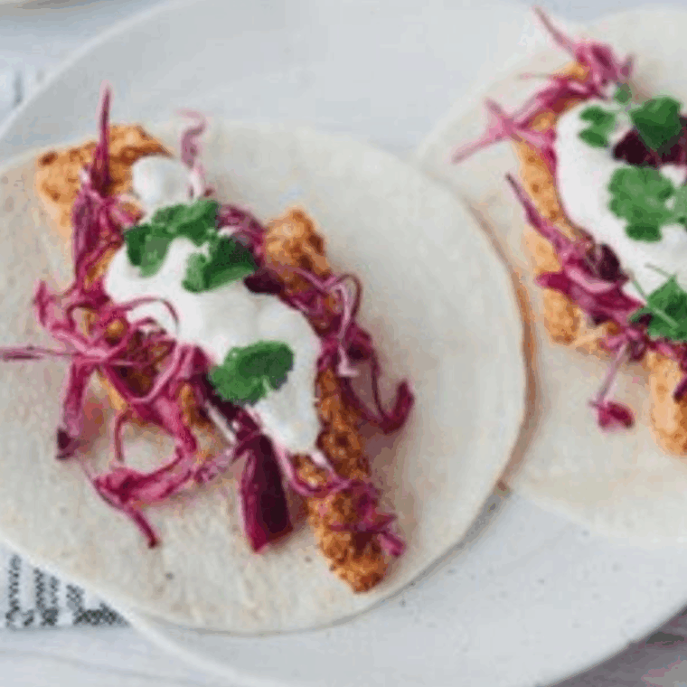 Blackened tilapia fish tacos with cabbage slaw and lime wedges.
