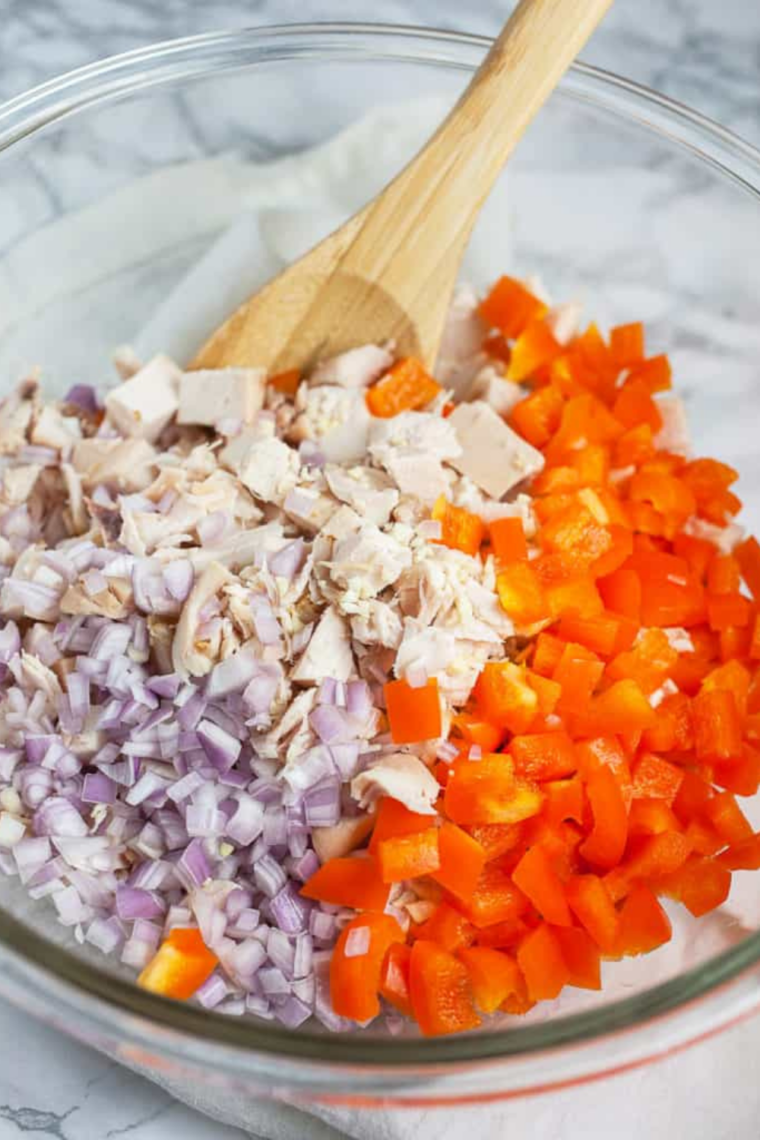 Shredded chicken, corn, sun-dried tomatoes, and bell pepper being folded into chipotle mayo.