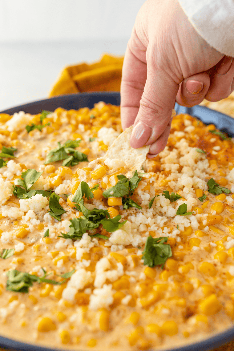 Creamy air fryer elote dip made with roasted corn, Cotija cheese, Mexican cheese blend, and cilantro served warm with tortilla chips for dipping