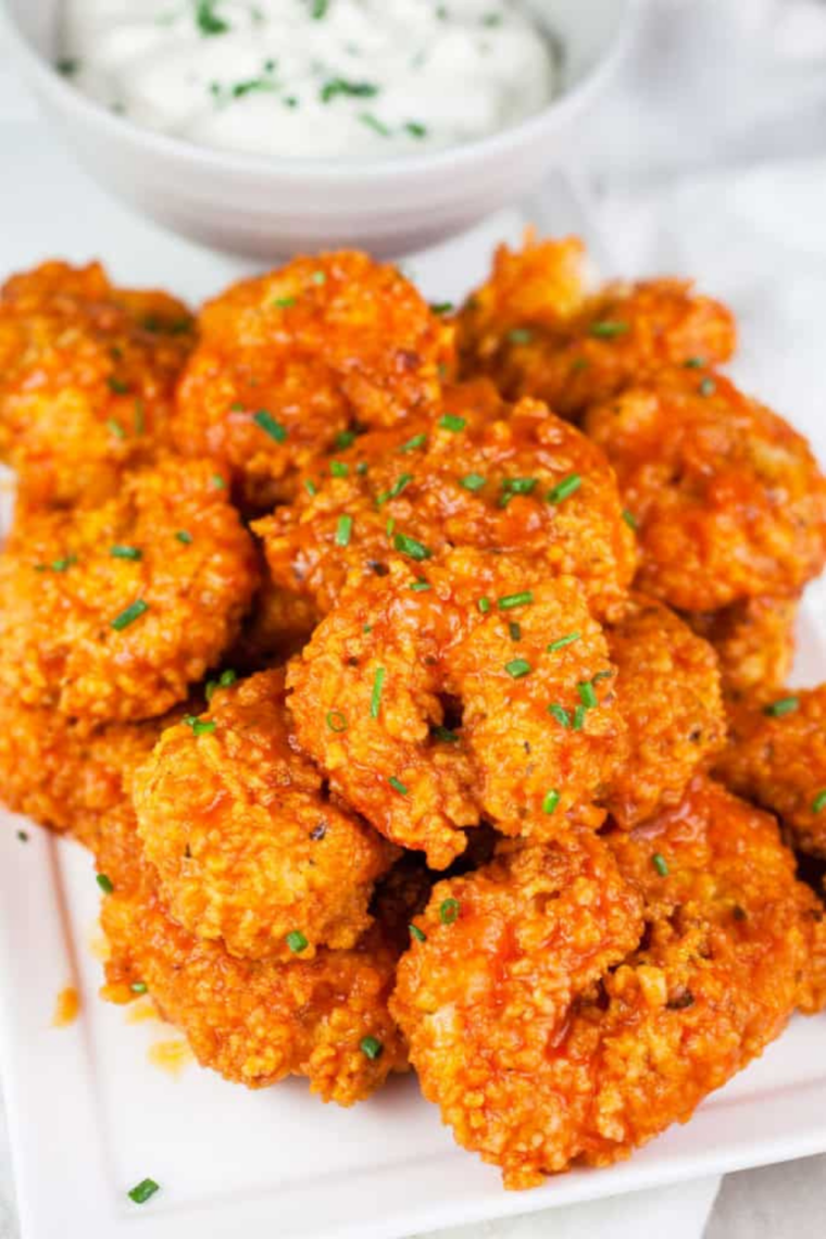 Crispy air fryer buffalo shrimp coated in spicy Hooter’s-style sauce, served on a plate with garnish.