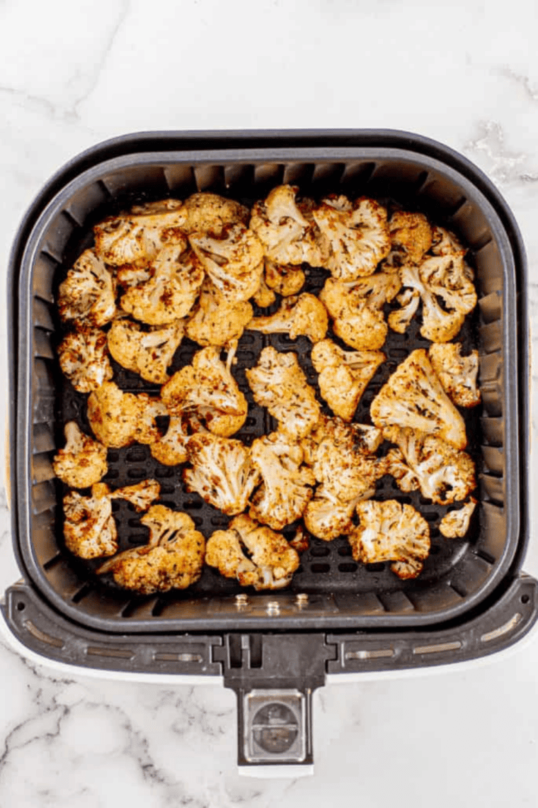 Air fryer cauliflower tossed with halved cherry tomatoes, ready to serve with dipping sauce.