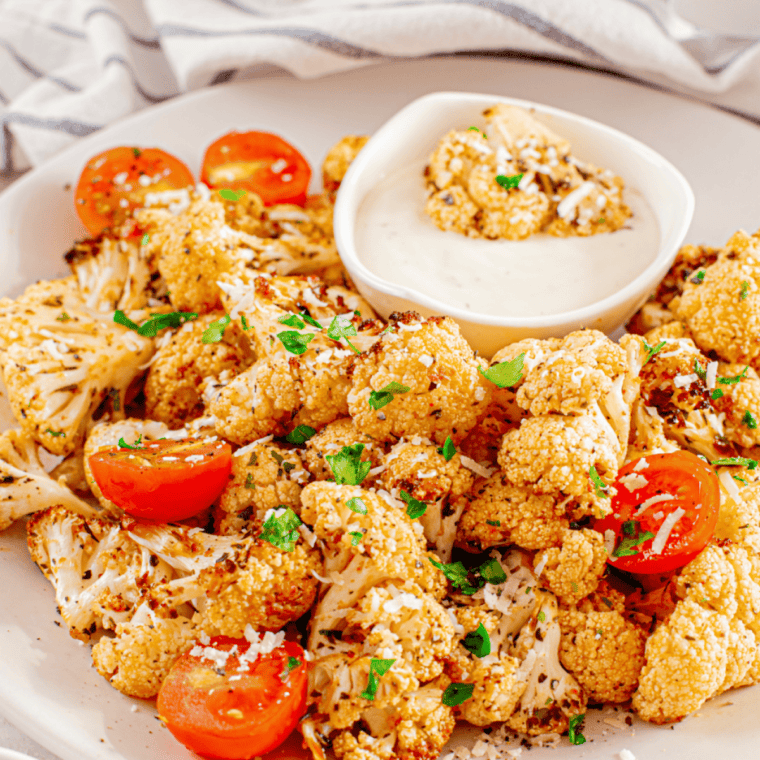 Air fryer roasted cauliflower florets with caramelized tomatoes served in a bowl.
