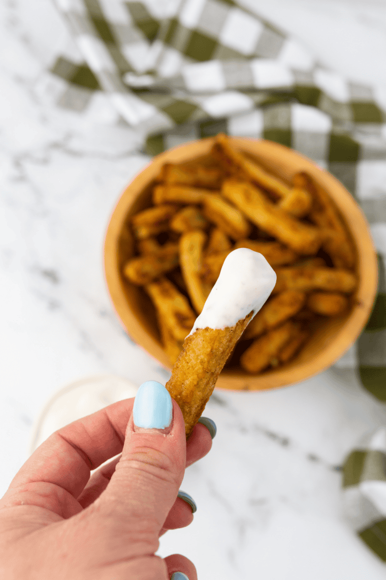 Air fryer basket filled with golden, crispy frozen zucchini fries.