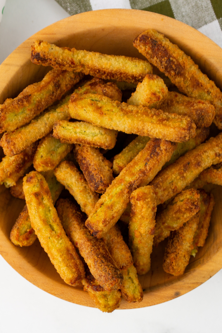 Crispy golden frozen zucchini fries cooked in the air fryer, served on a plate with dipping sauce