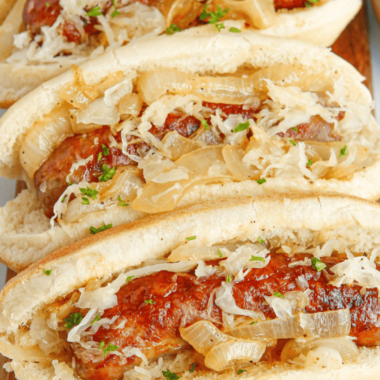 Air fryer hot dogs in buns topped with sauerkraut and spicy brown mustard, served New York style and ready to eat.