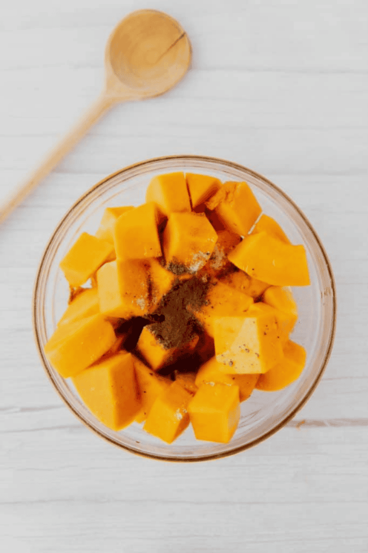 Sweet potato cubes tossed with olive oil and seasonings in mixing bowl until coated