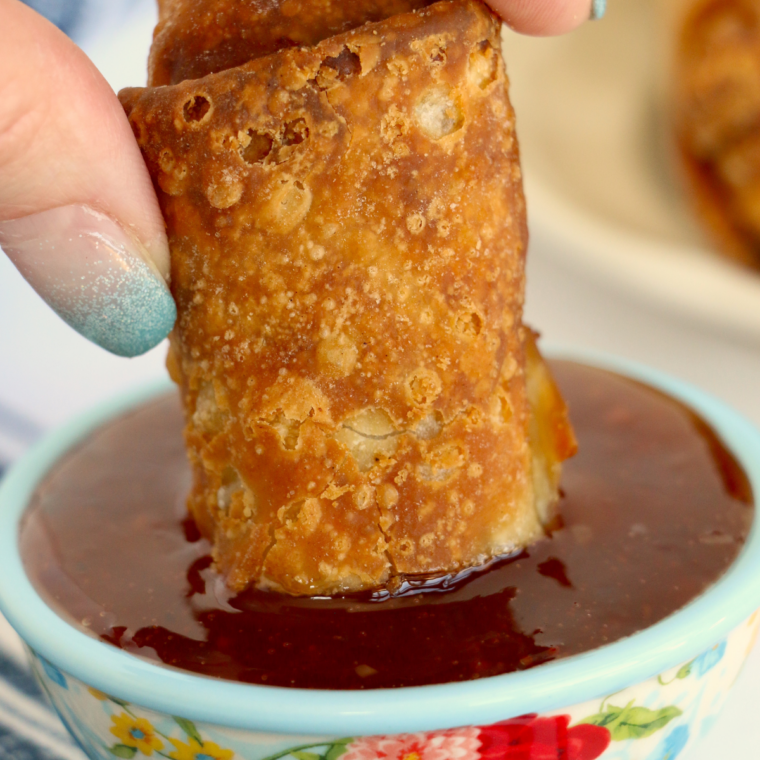 Crispy air fried Chung's egg roll being dipped into sweet and sour sauce