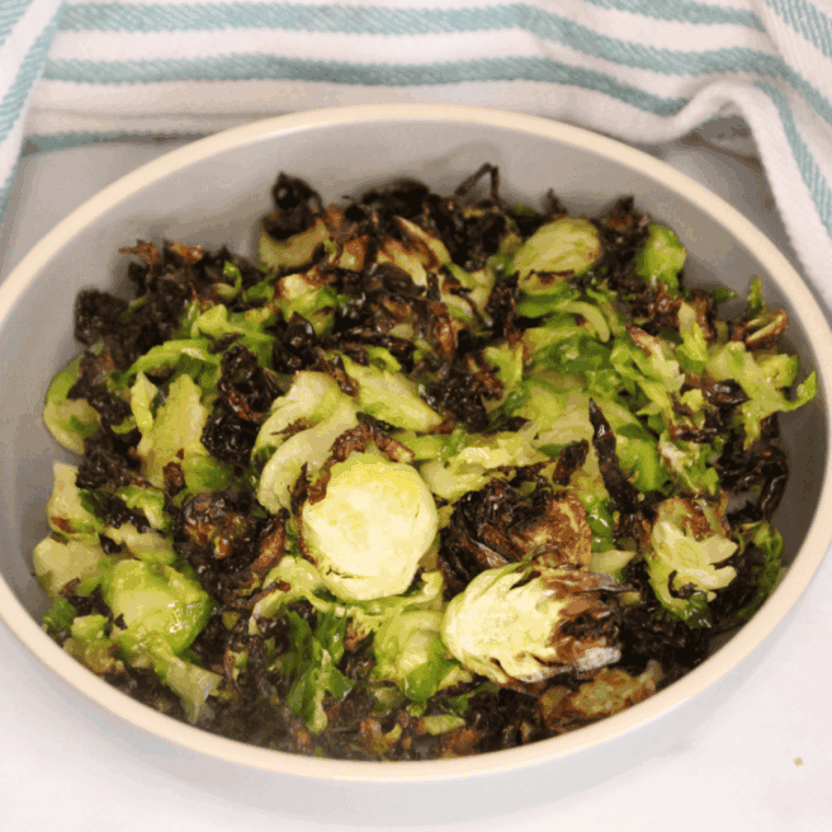 Crispy shaved Brussels sprouts in an air fryer basket, golden and seasoned
