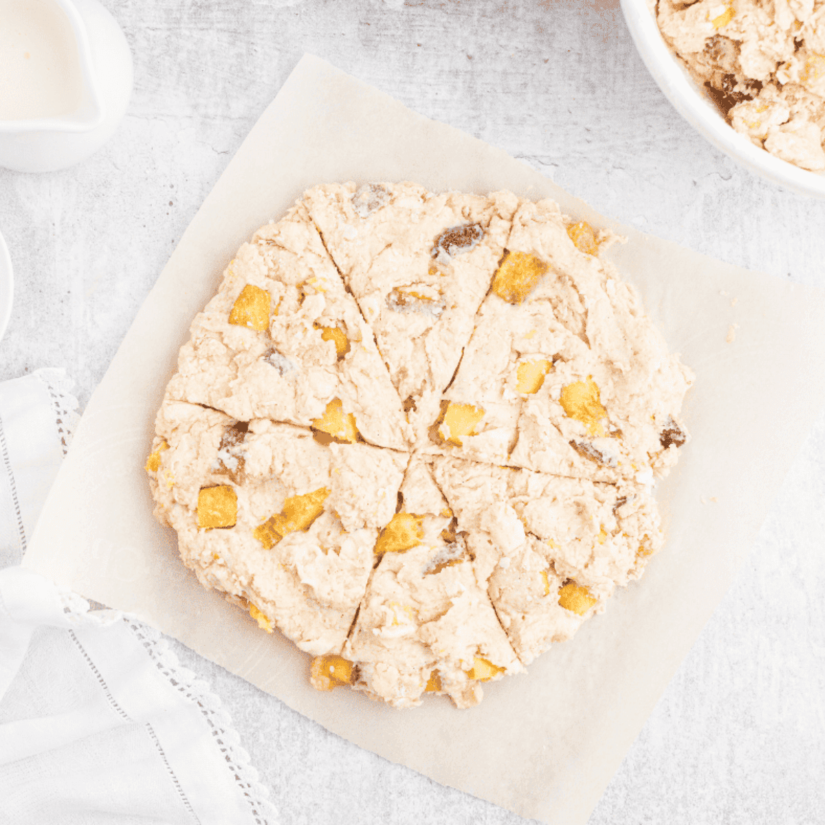 Mixing buttermilk, almond extract, and chopped peaches into scone dough, then shaping into circles on a floured surface.