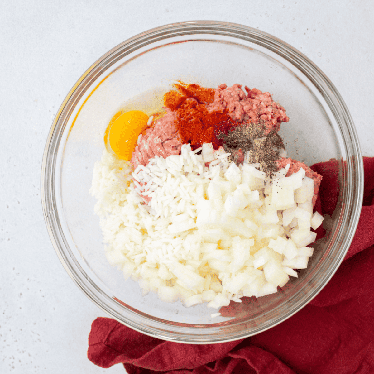 Mixing ground beef, rice, onions, egg, paprika, and seasonings in a large bowl for stuffed cabbage rolls.