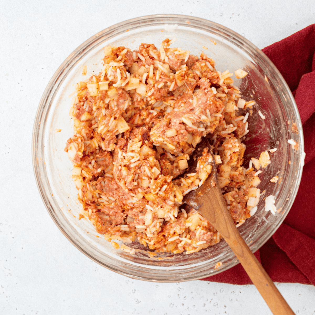 Combining ground beef, rice, onions, egg, paprika, and seasonings in a large bowl to prepare stuffed cabbage rolls.