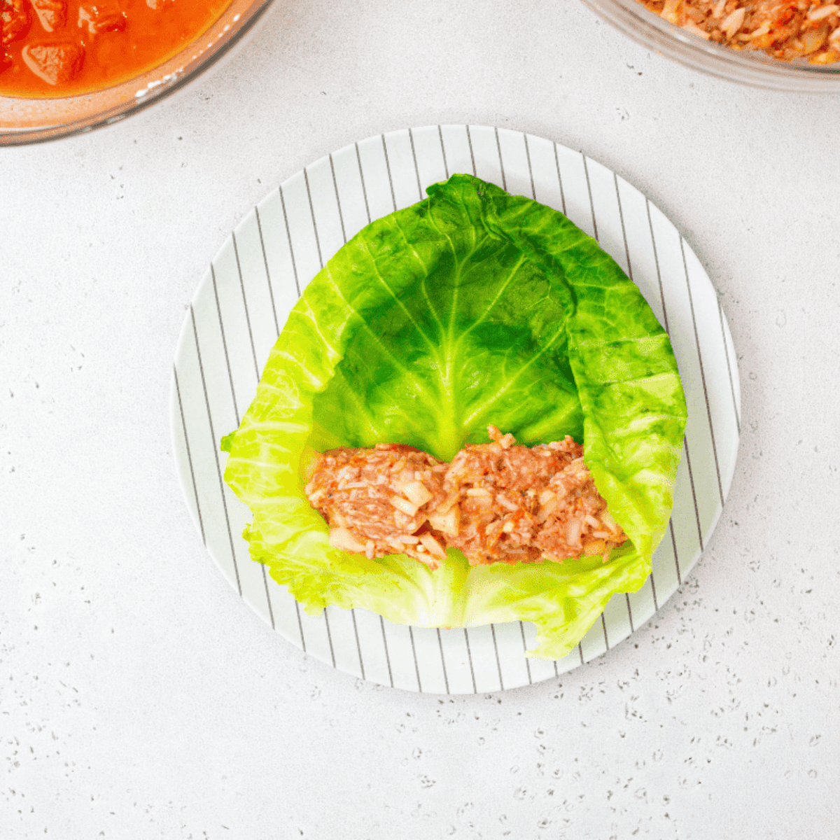 Placing approximately three tablespoons of beef filling onto a cabbage leaf and rolling it up for stuffed cabbage rolls.