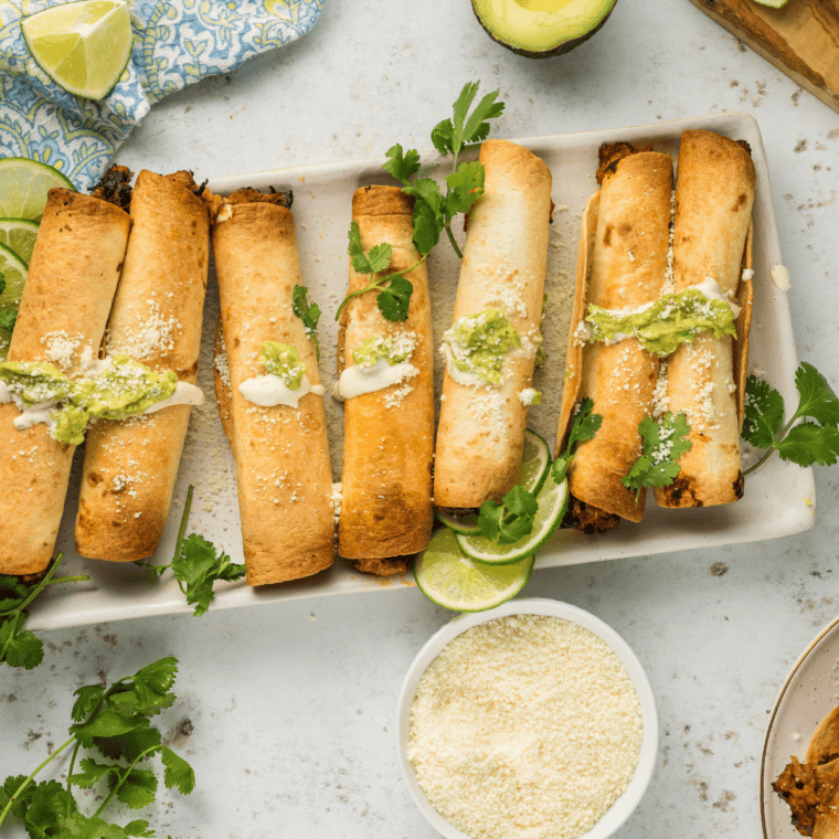 Crispy bean and cheese air fryer taquitos on a plate with salsa