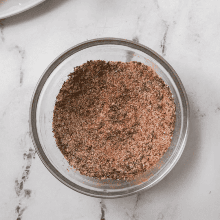 Chicken being rubbed evenly with homemade McCormick Perfect Pinch seasoning on all sides.