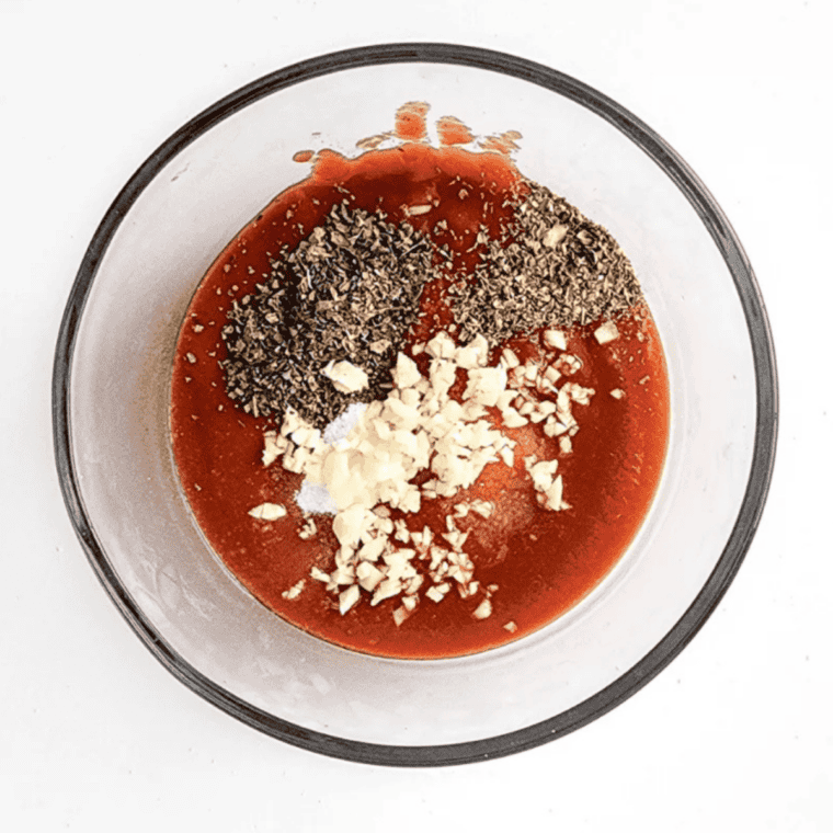 Mixing tomato paste, water, olive oil, and seasonings in a medium bowl for pizza sauce.